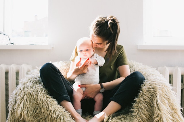 woman holding baby while sitting on a fur bean bag