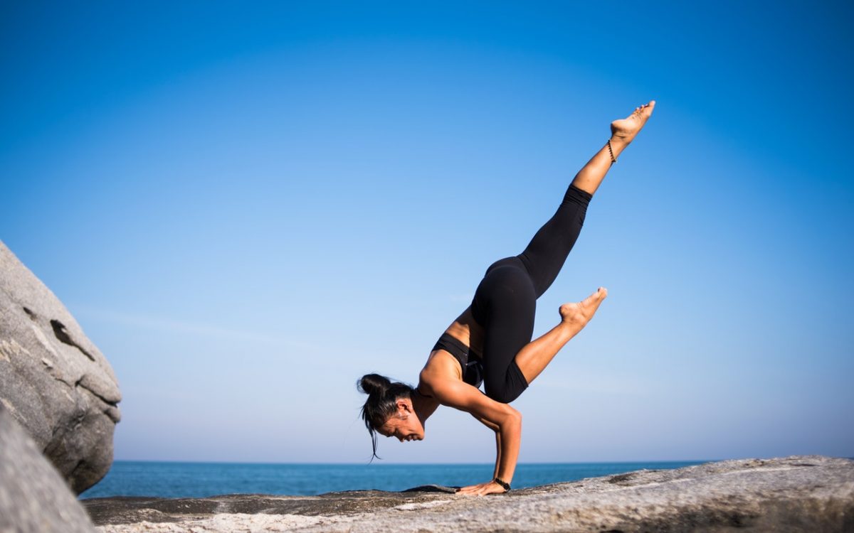 woman doing yoga on rocks with ocean view